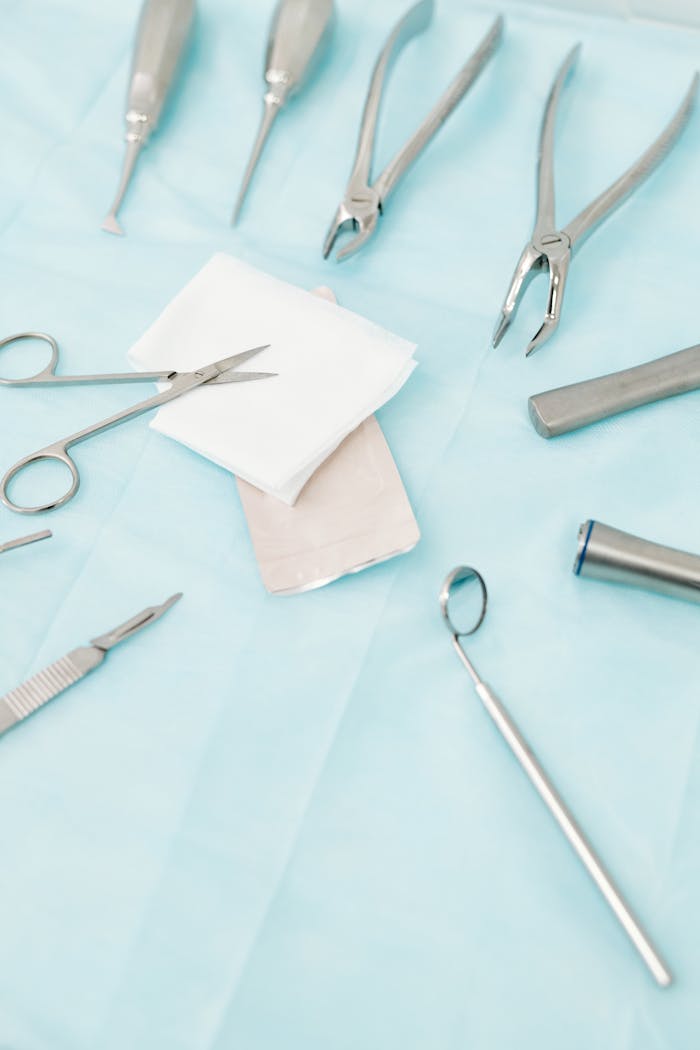 A close-up view of various stainless steel dental instruments arranged on a sterile blue background.